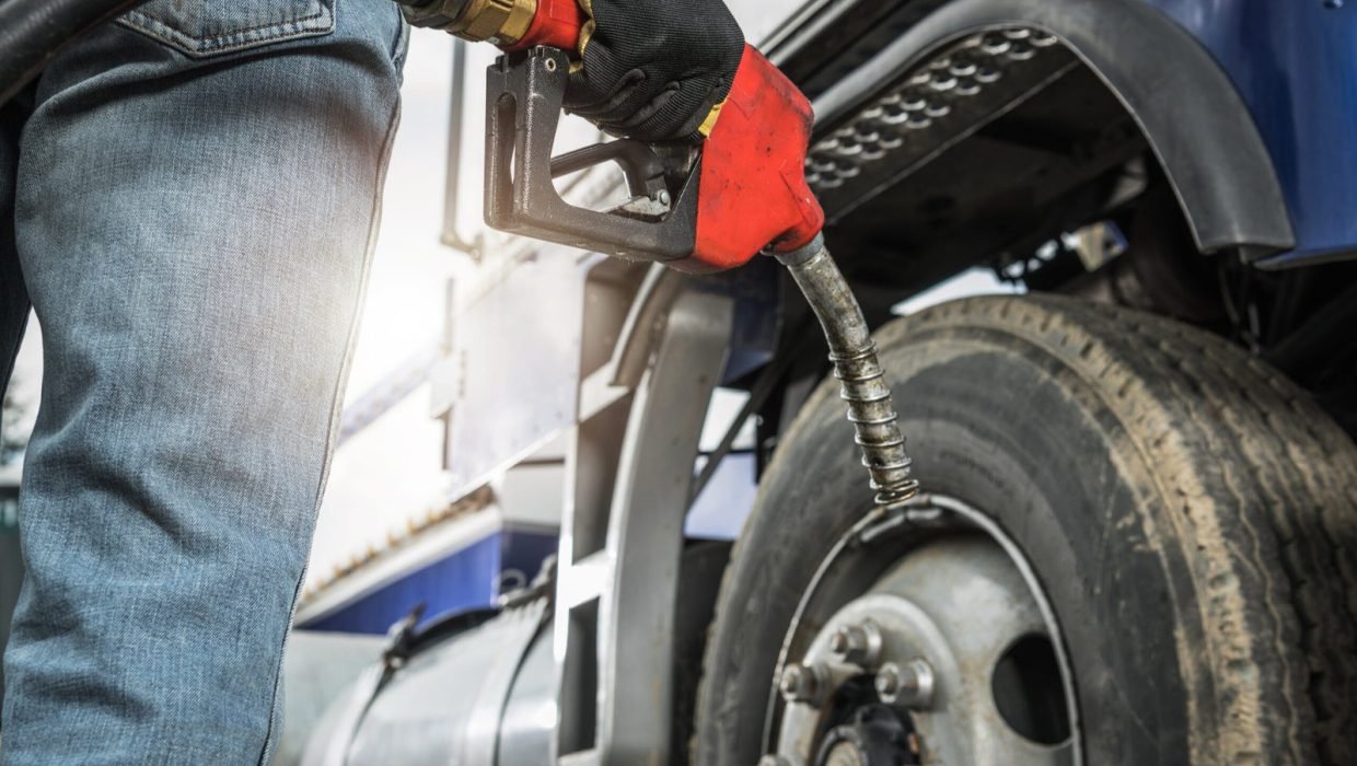 Aged Semi Truck Driver About to Refuel His Tractor Truck Holding Diesel Pump Nozzle in His Hand. Heavy Duty Transportation and Fuel Shortage Concept.